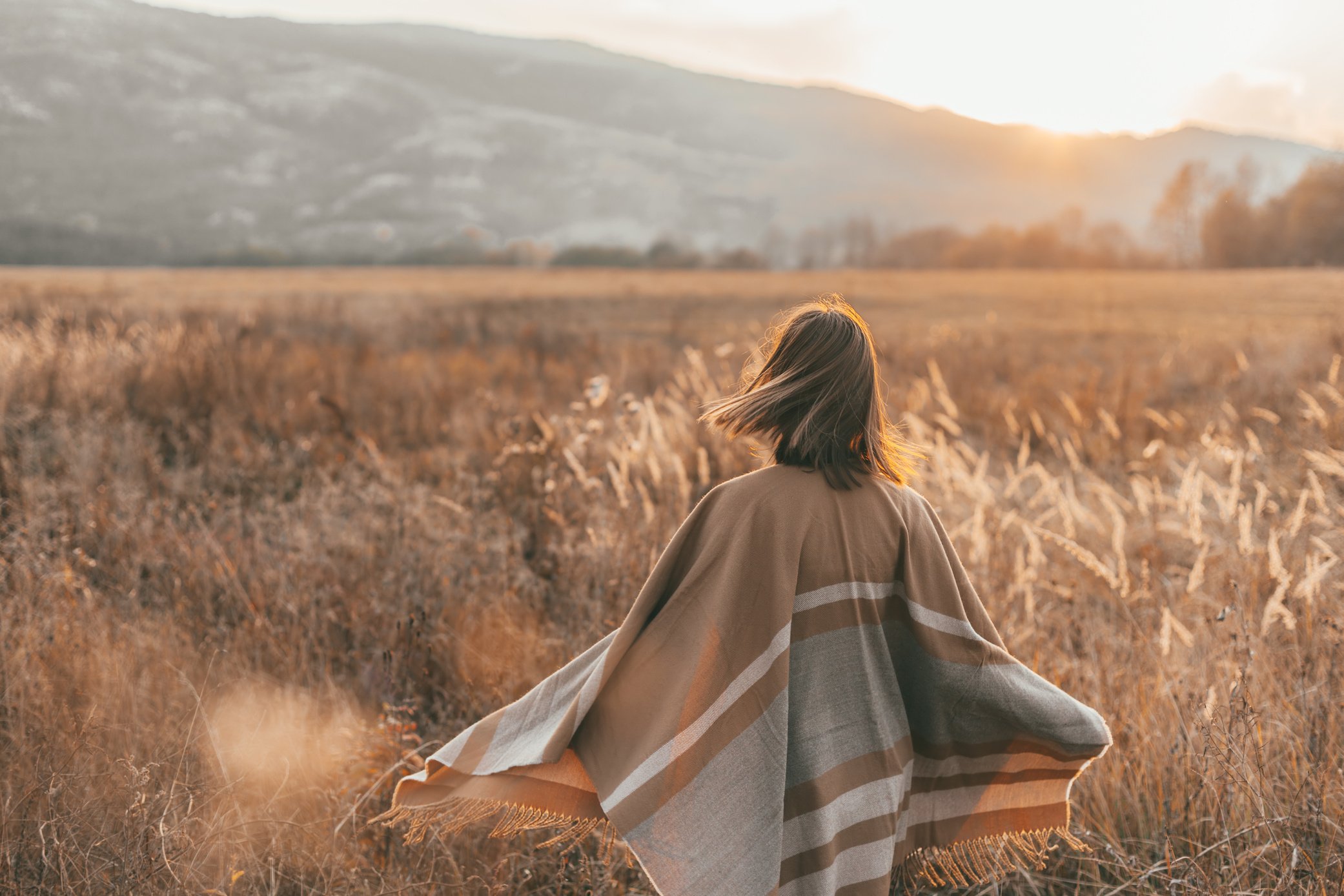 Girl in Poncho Alone in Field During Sunset